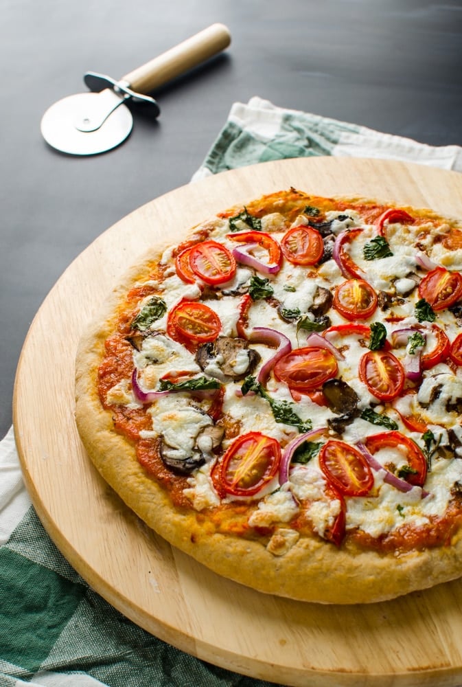 Tomato mushroom pizza on wooden base after baking.