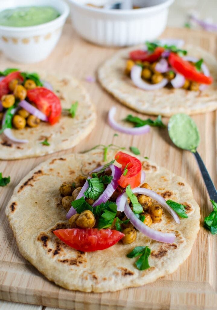 naan bread topped with roasted chickpeas, tomato and onion slices.