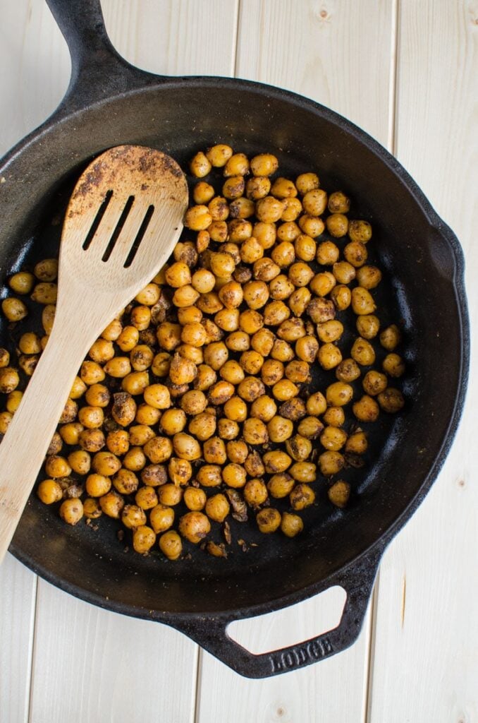 roasted chickpeas in a cast iron pan with wooden spatula.