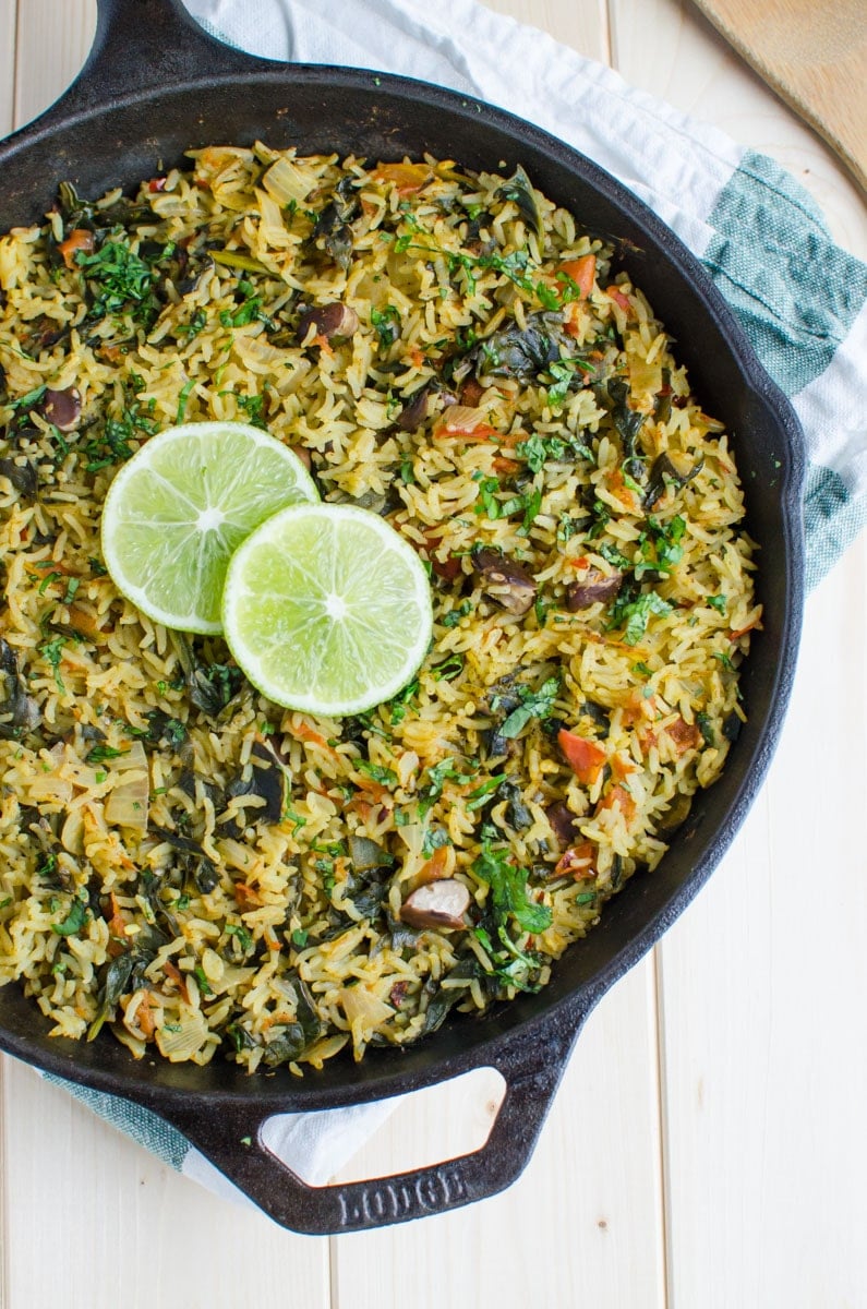 Healthy spinach rice with beans in a cast iron skillet. It is garnished with lime slices and is ready to serve.