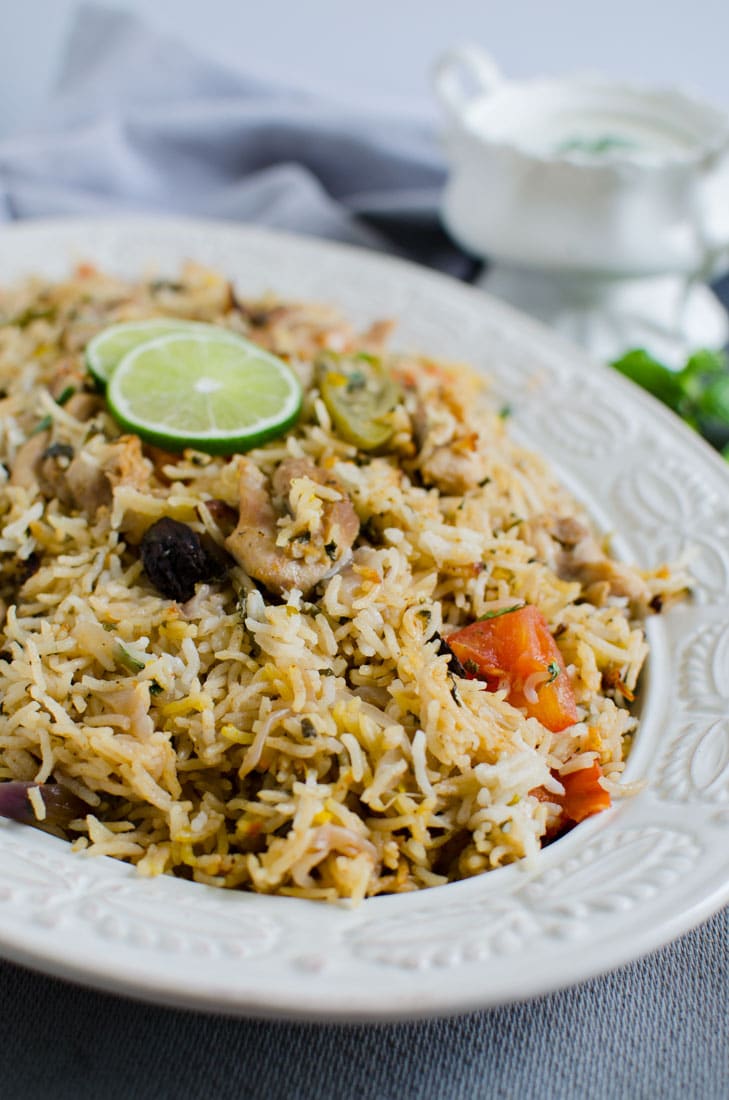 Side view of one pot chicken biryani rice in a large platter and garnished with sliced lime.