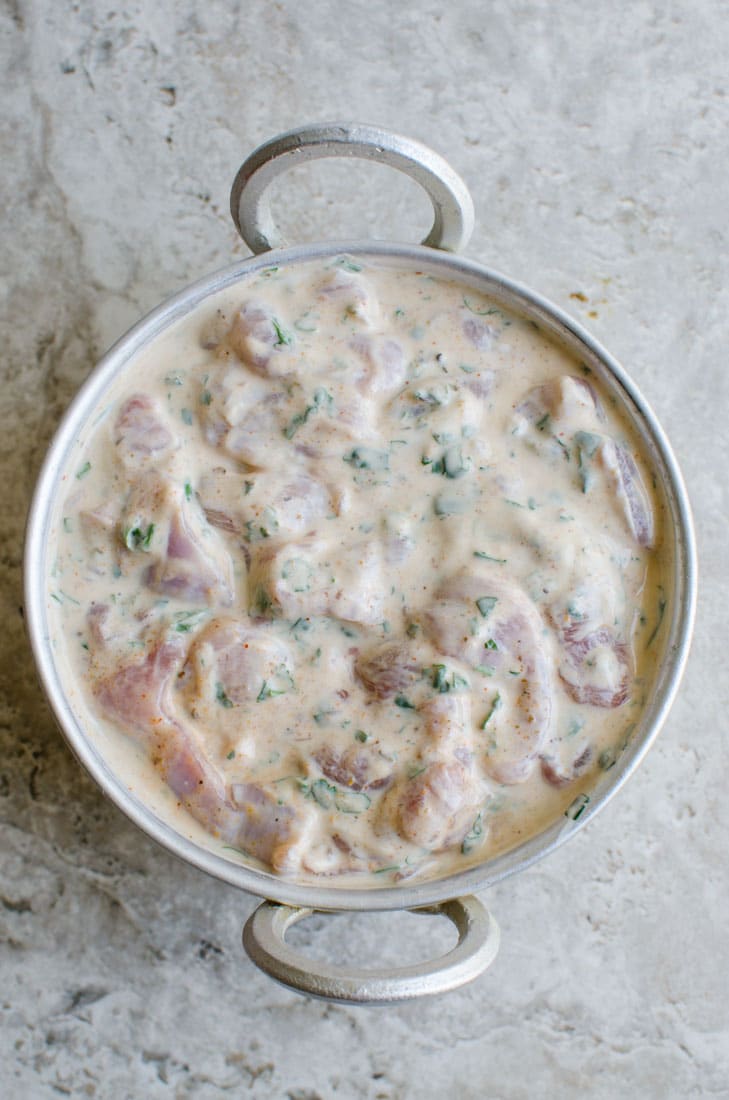 Marinated chicken with biryani masala and yoghurt in a mixing bowl .