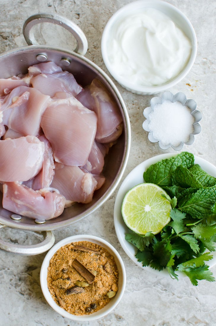 Raw chicken, plain yoghurt, salt, fresh herbs, lime and biryani masala for making biryani rice.