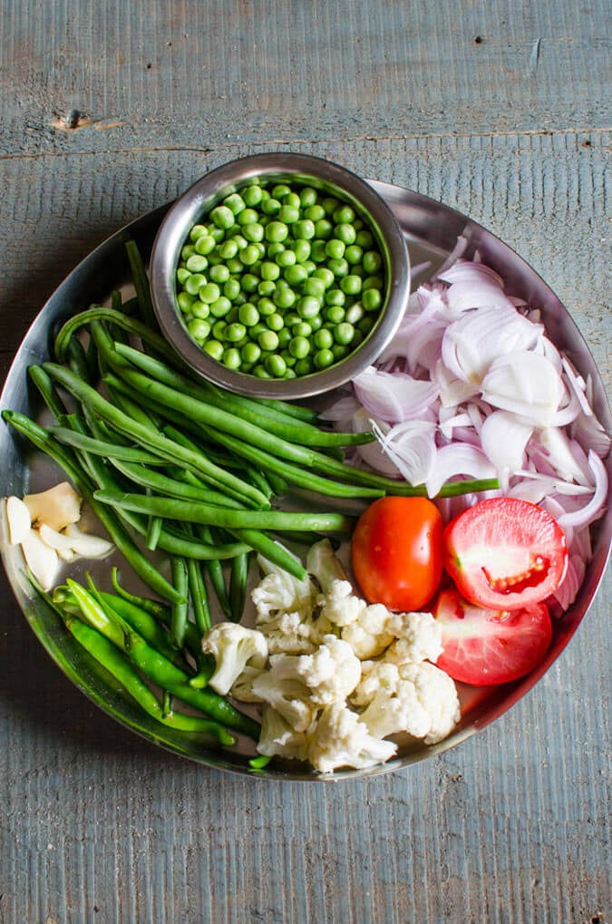 Ingredients such as peas, beans, onion, cauliflower etc. gathered in a large metal plate for making veg biryani.