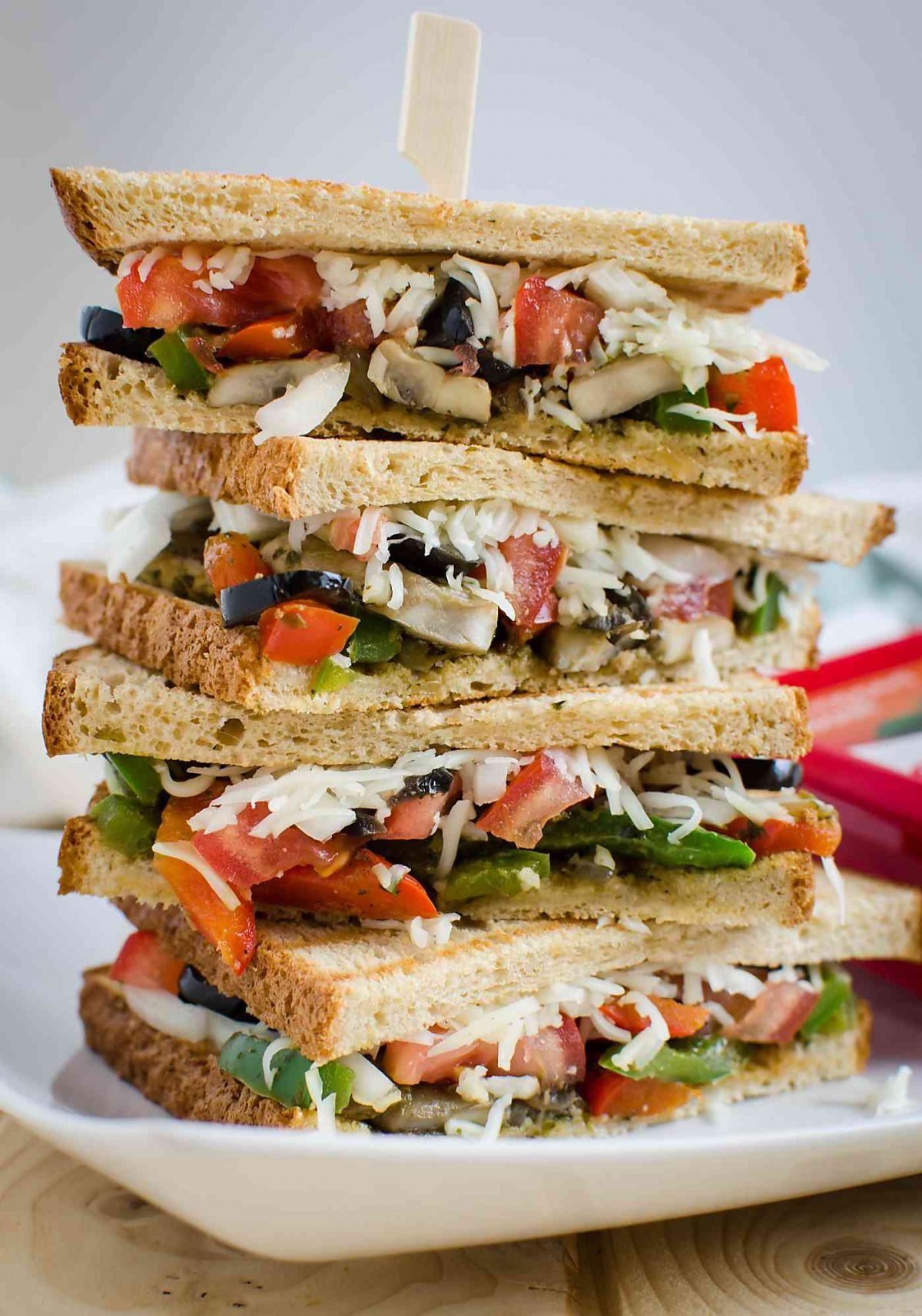 Italian veggie sandwich with peppers, olives and fresh mozzarella cheese stacked on each other.