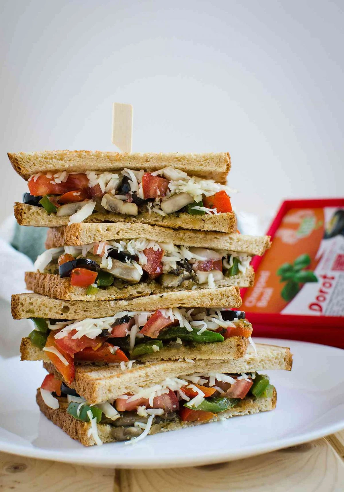 Italian veggie sandwich with peppers, olives and fresh mozzarella cheese stacked on each other.