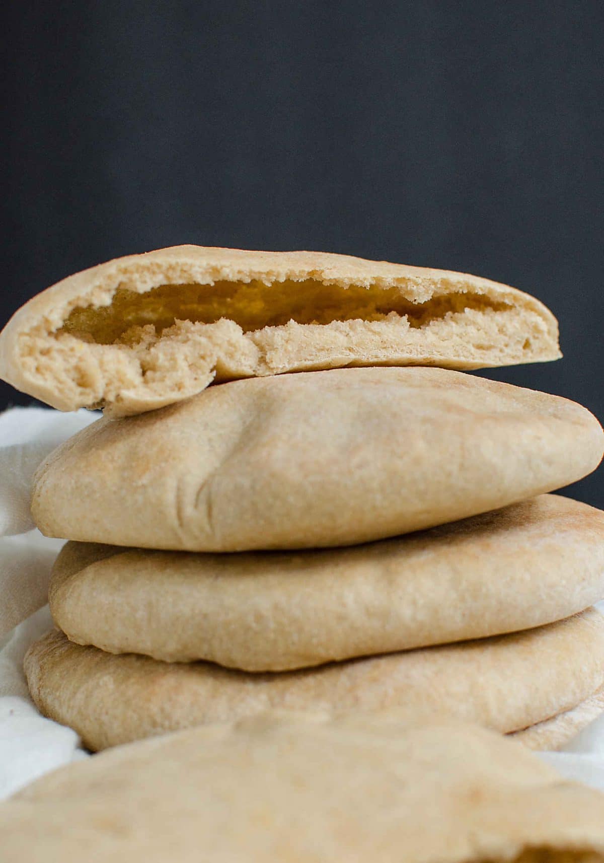 Stack of baked pita bread is ready to serve. Upper bread on the stack cut into half showing the inside texture. 