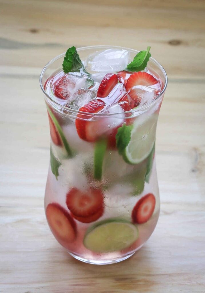 Strawberry detox water with ice in large glass jar.