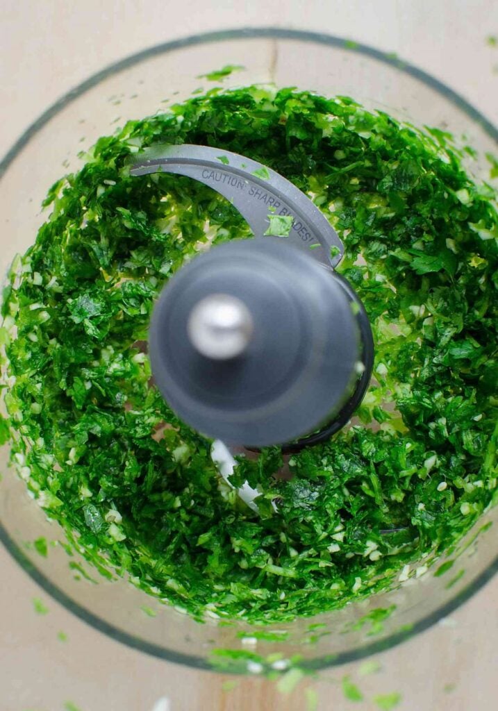 Minced fresh cilantro with jalapeño and garlic in food processor jar.