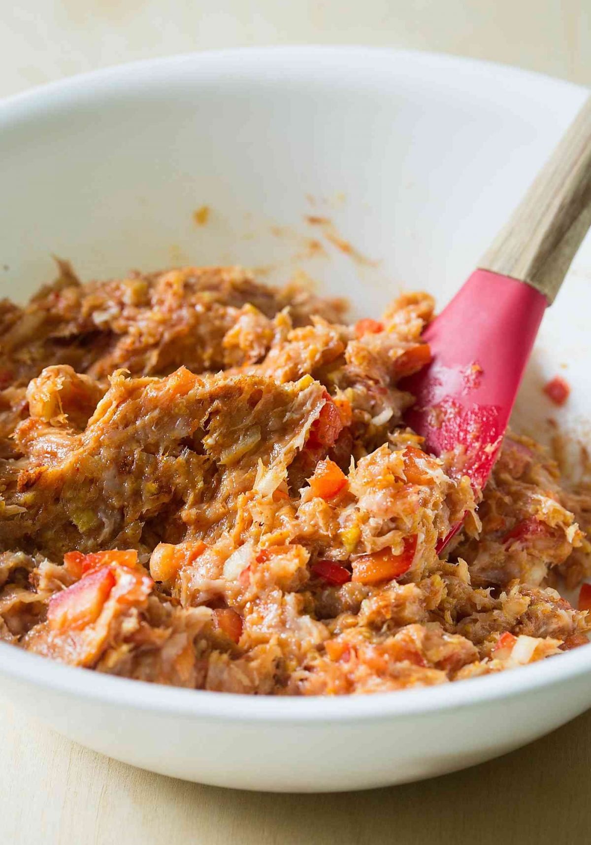 Mixture of ground chicken with diced pepper, onion and spices in a mixing bowl ready to prepare burger patties.