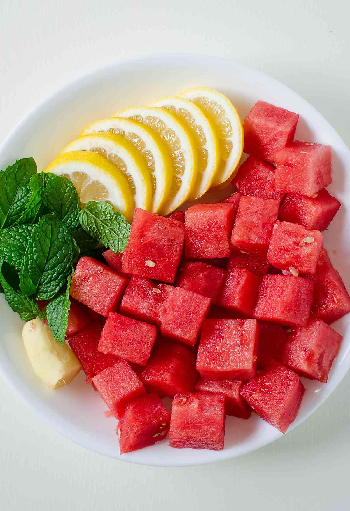 
Watermelon cubes, lemon slices, ginger and mint in a ceramic bowl.