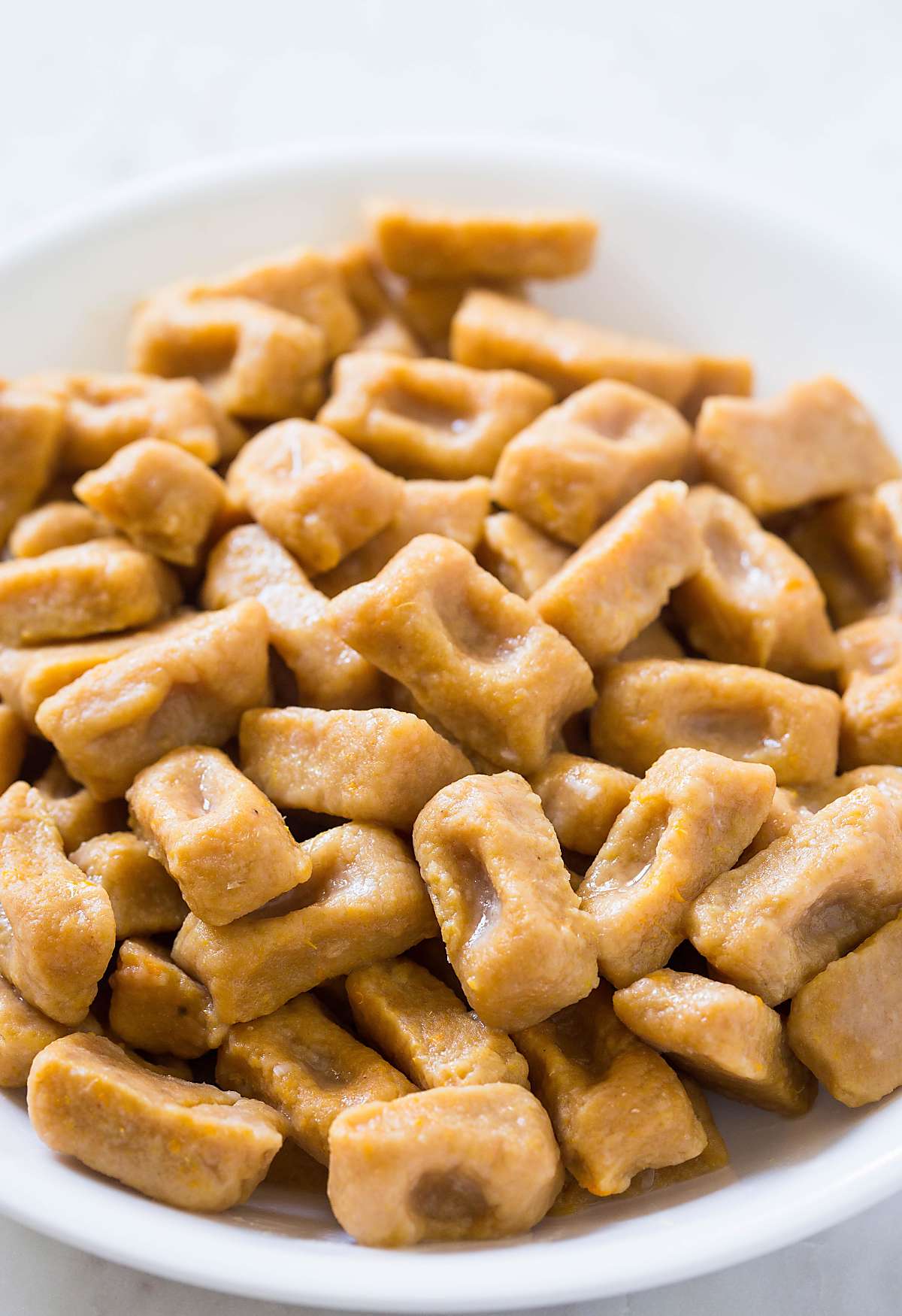 Cooked sweet potato gnocchi in a white ceramic bowl.