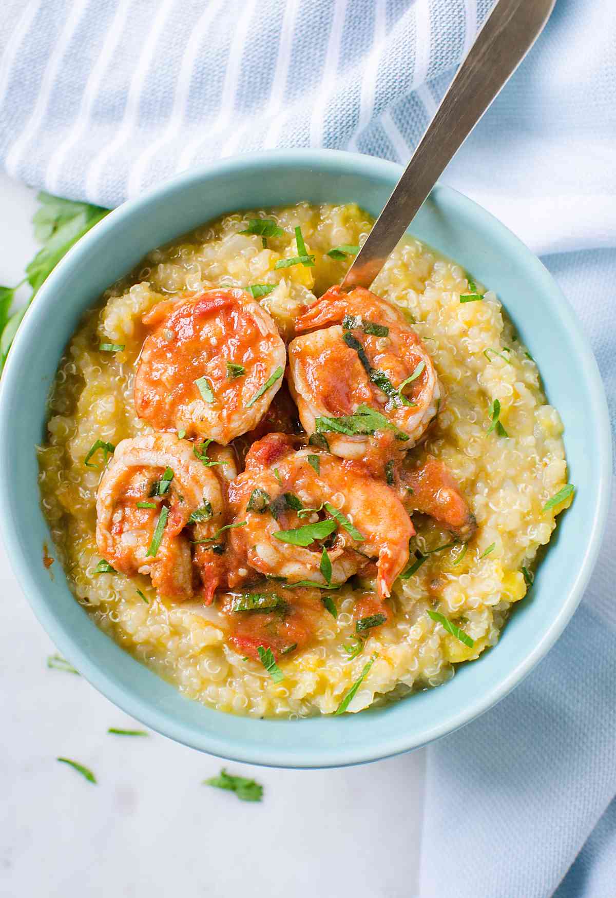 roasted healthy butternut squash quinoa risotto served with shrimp in tomato sauce in a serving bowl with serving spoon.