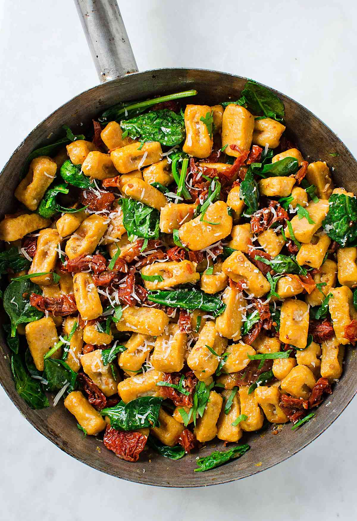Sweet potato gnocchi with spinach and sundried tomato in large pan.