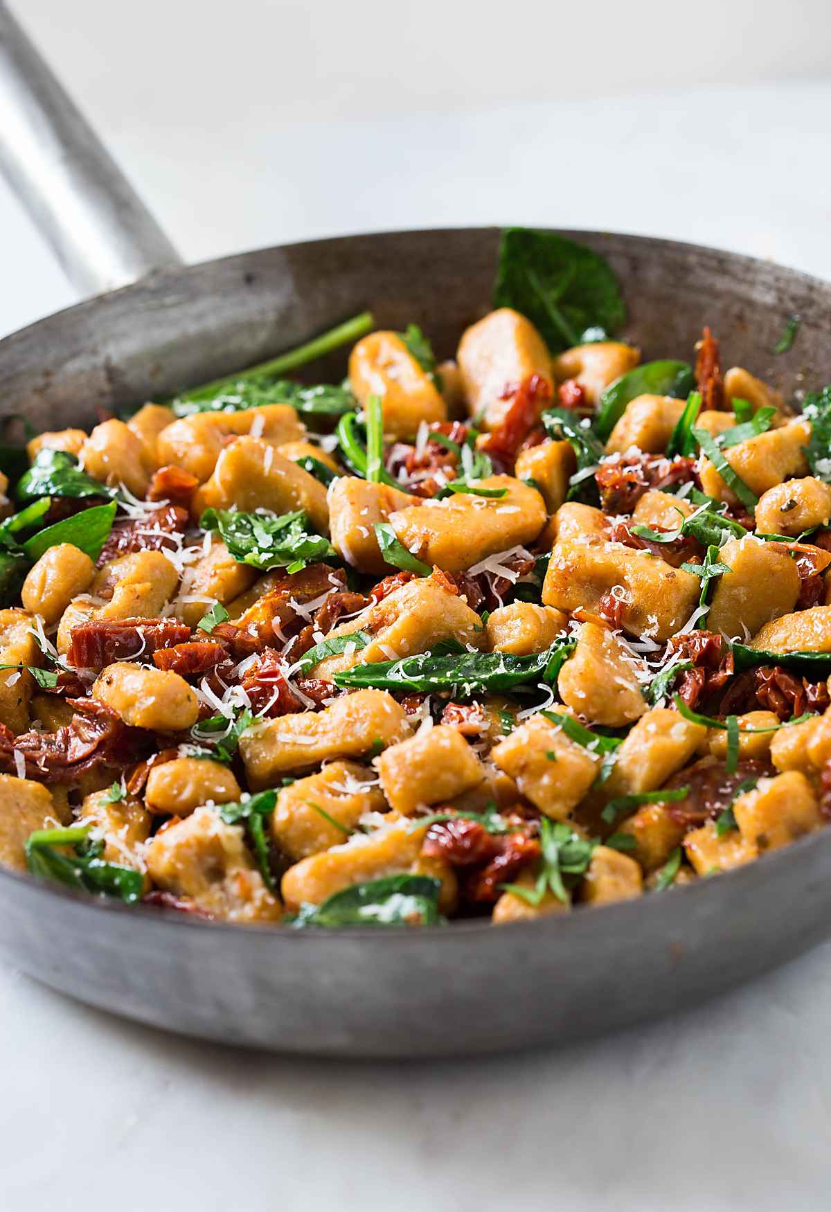 Sweet potato gnocchi with spinach and sundried tomato in large pan.