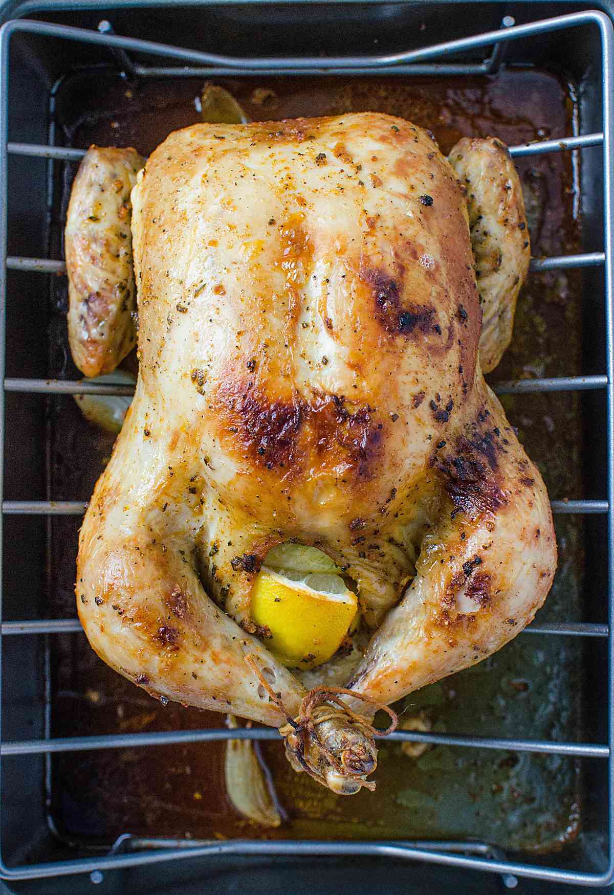 Herb roasted whole chicken in a baking tray.