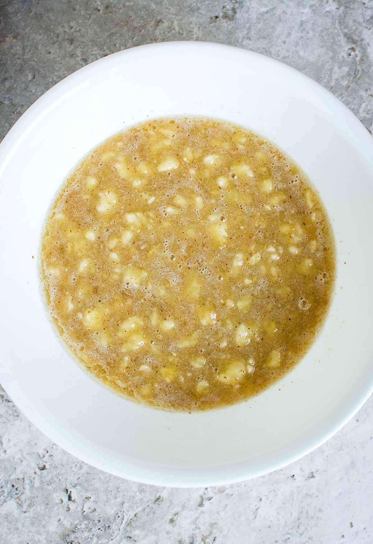 Mixture of mashed banana, nut butter and agave in a mixing bowl.