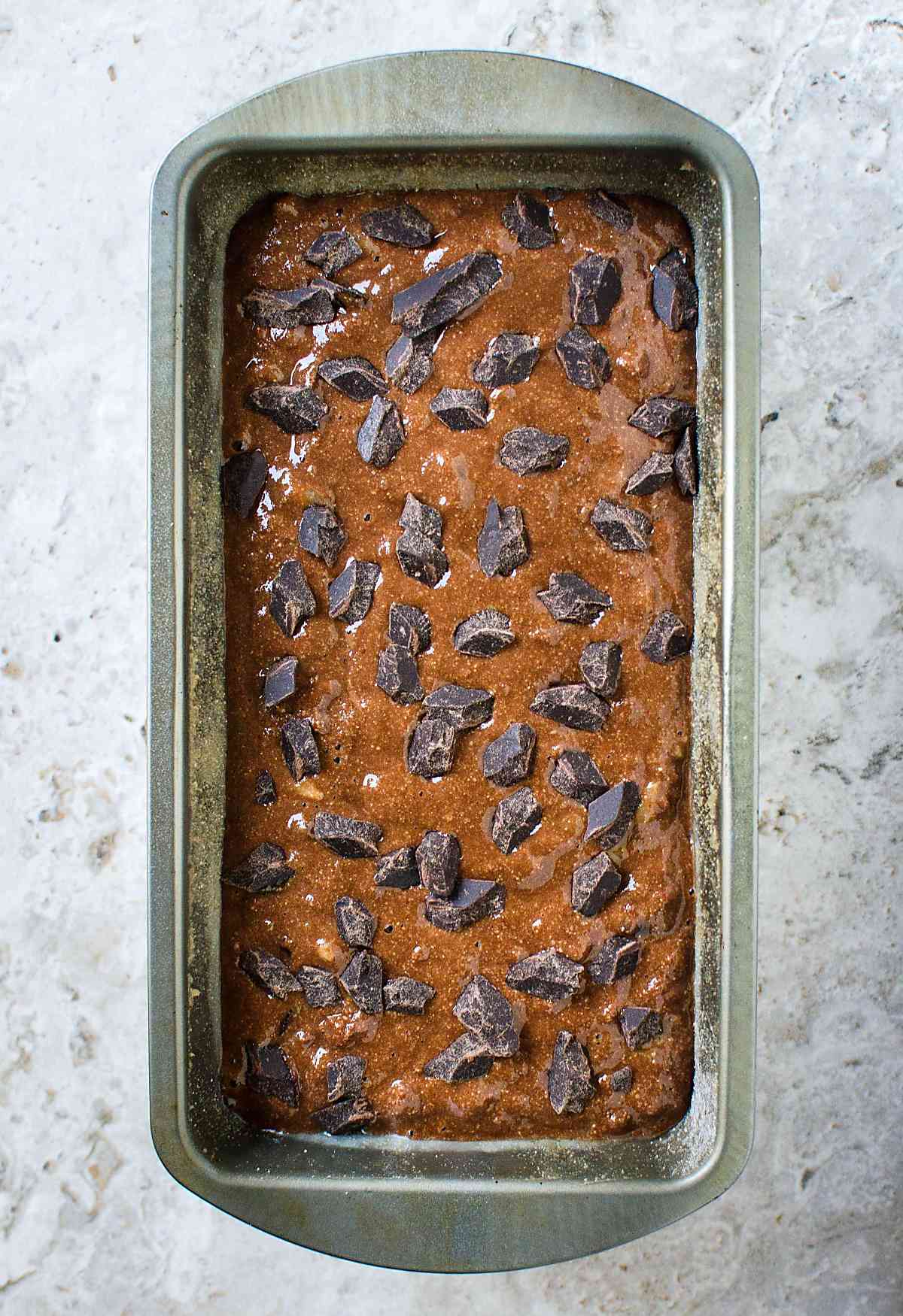 Chocolate oatmeal banana bread batter in a metal bread loaf pan ready to bake.