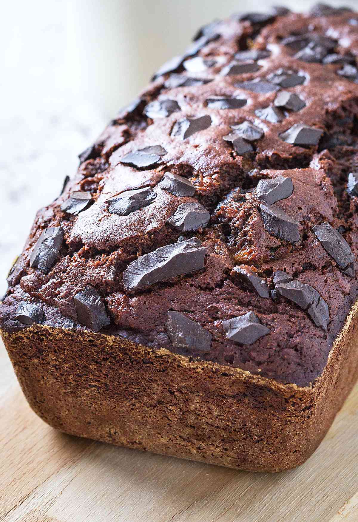 Chocolate oatmeal banana bread loaf on wooden cutting board.