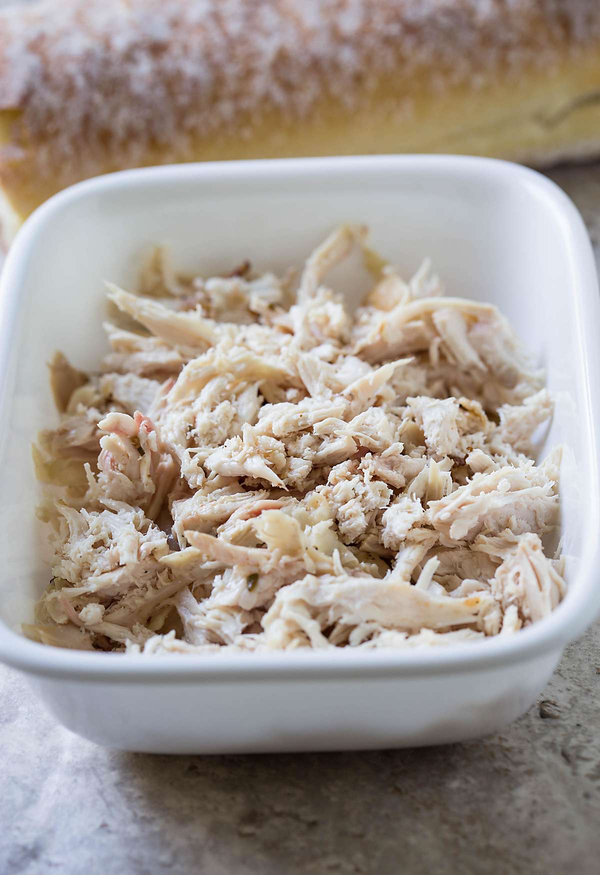 Shredded leftover chicken in a ceramic bowl for making sandwich.