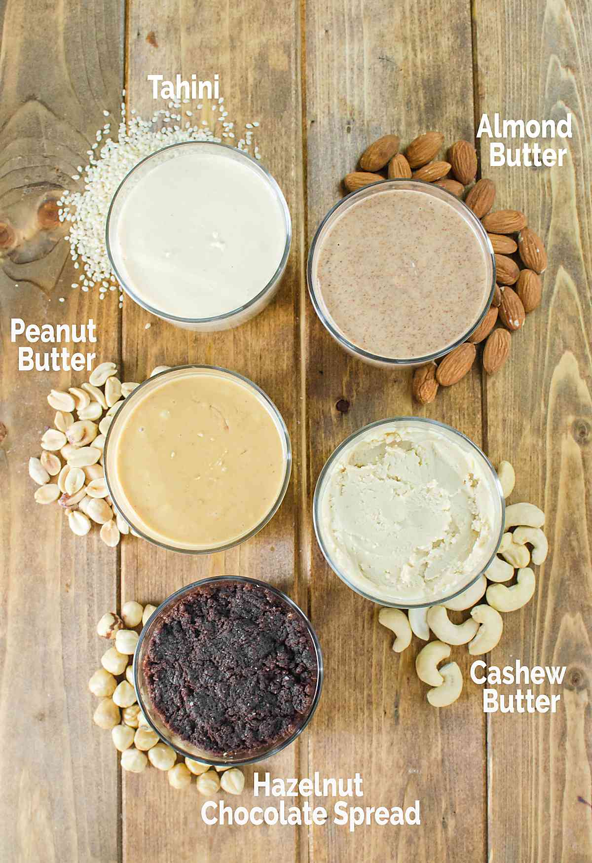 Different kinds of nut butter in small glass bowls.