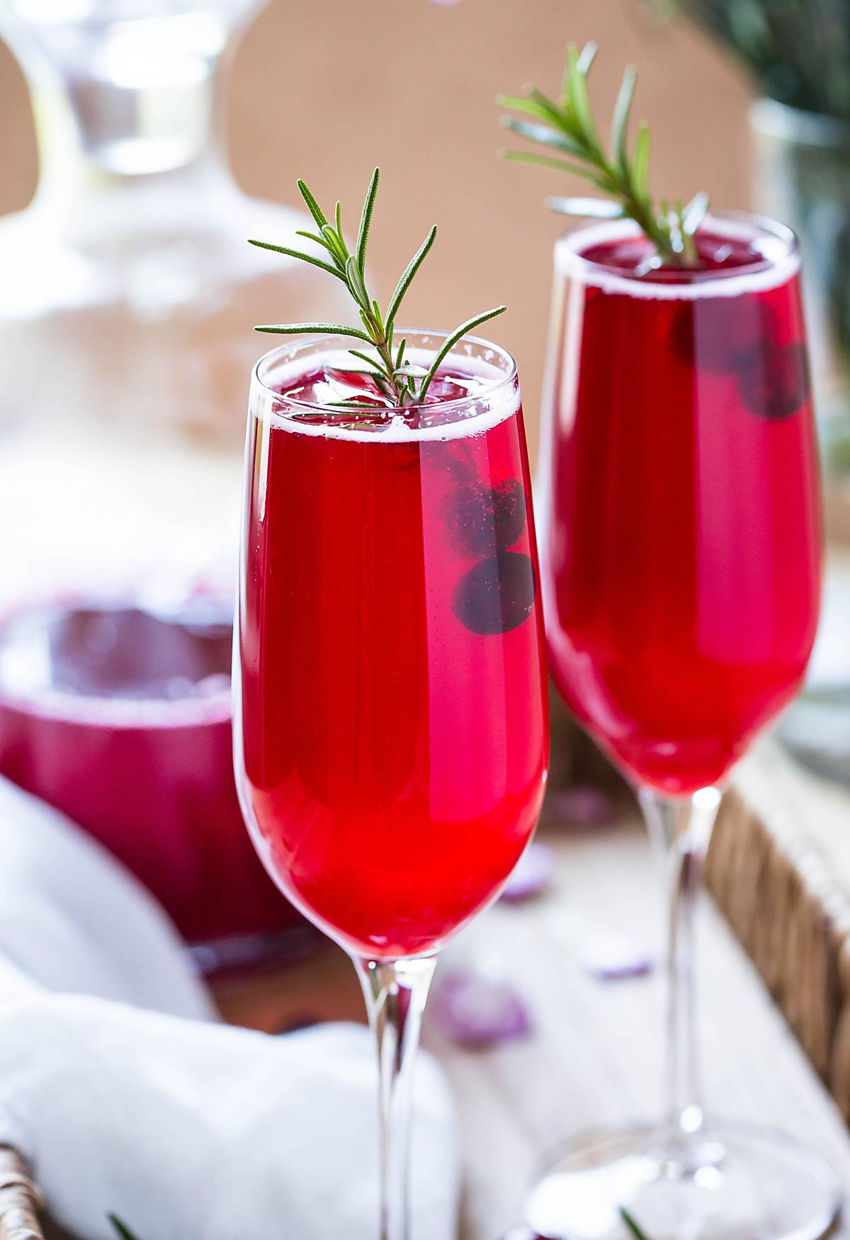 Festive non alcoholic cranberry drink served in champagne flutes and garnished with fresh rosemary spring and cranberries.