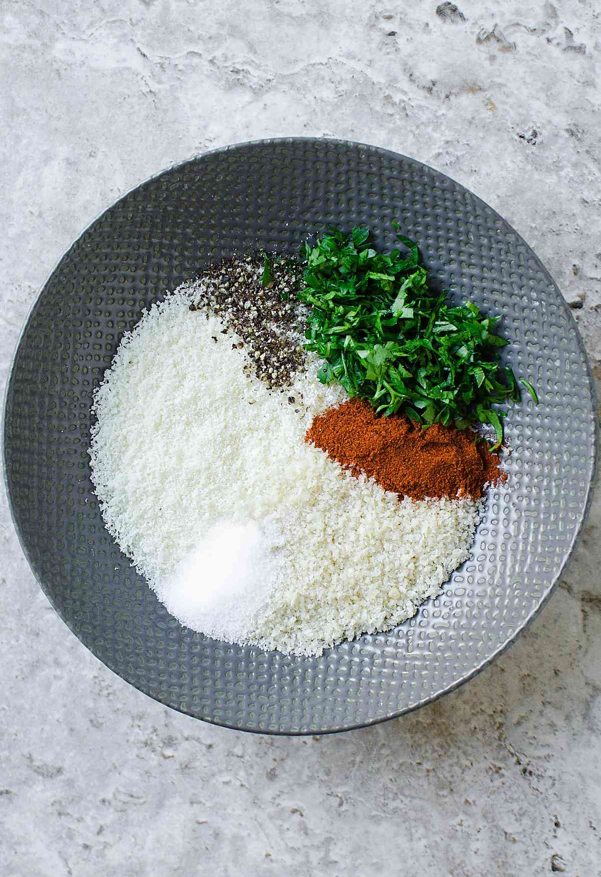 Parmesan cheese, bread crumbs, herbs and spices in a small mixing bowl.