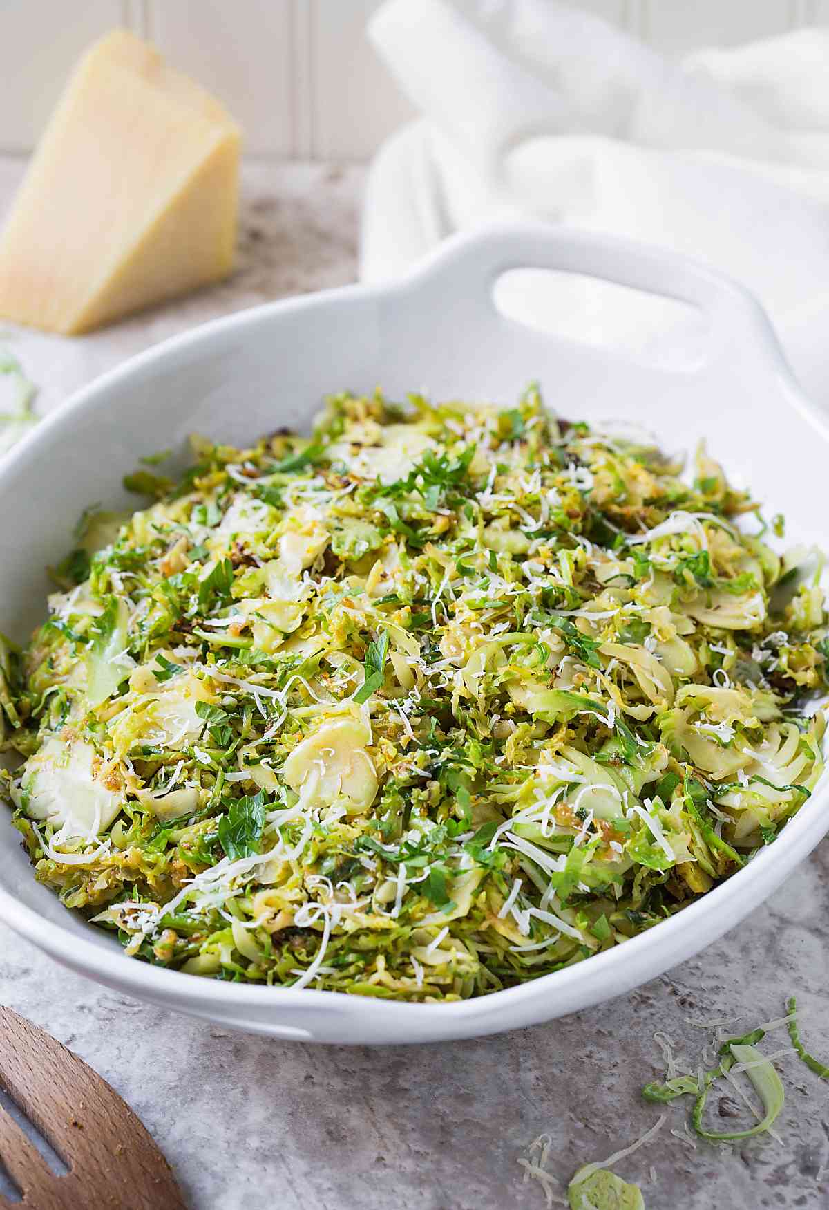 Image showing side view of shredded and sauteed garlic parmesan brussels sprouts in a serving bowl.