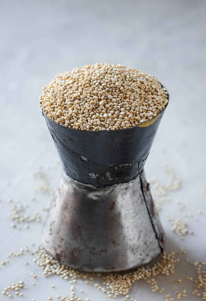 Raw quinoa in metal measuring cup.
