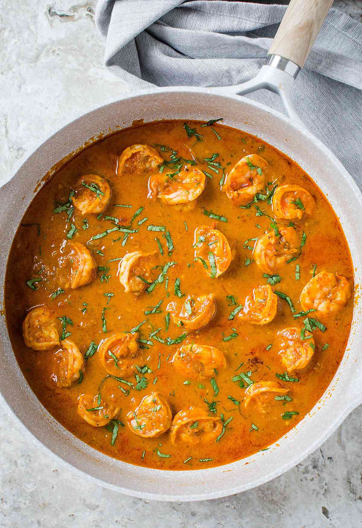 Image with fully cooked Indian coconut shrimp curry in a skillet.