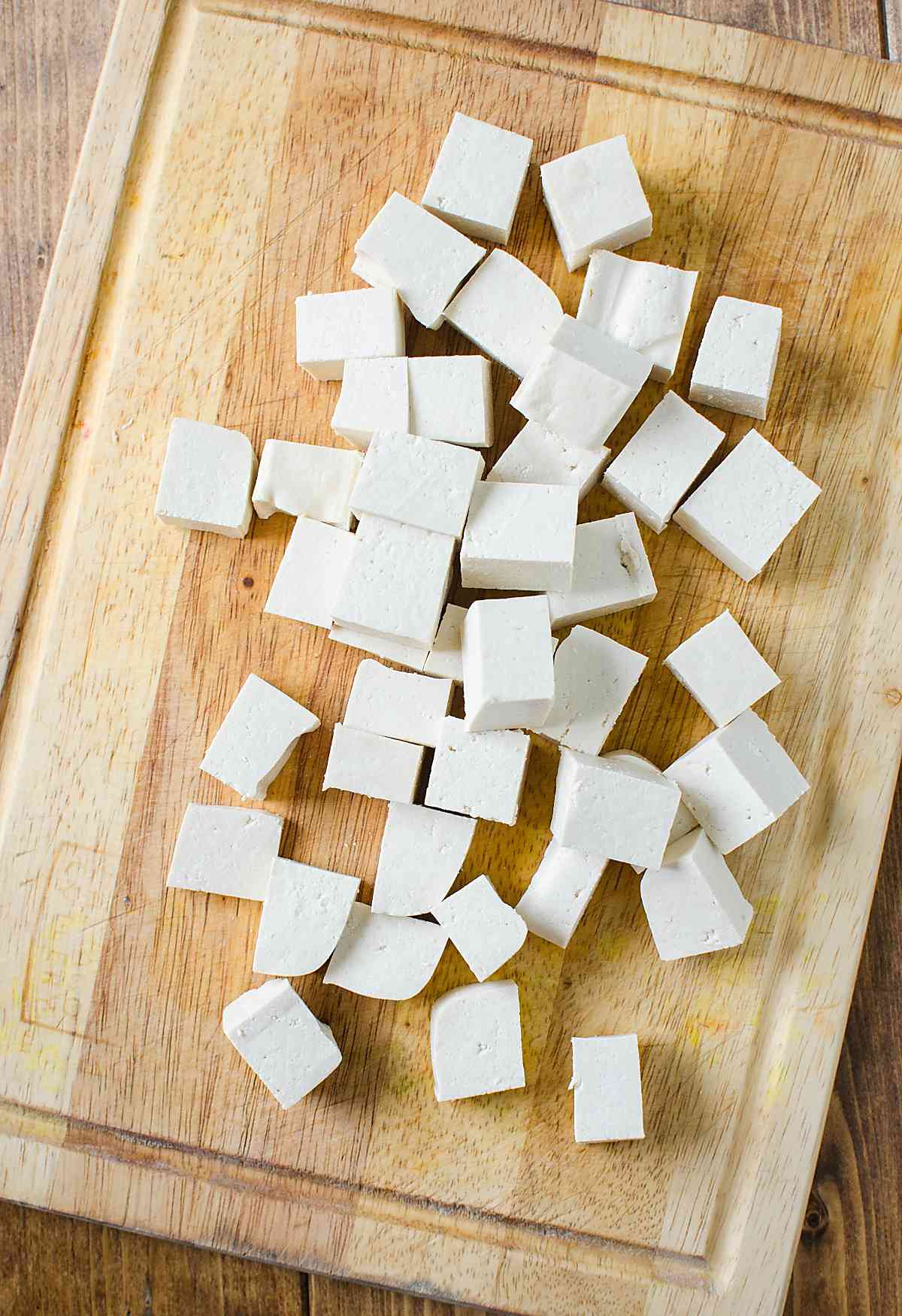Cutting tofu into bite-size pieces for making Asian chili garlic tofu.