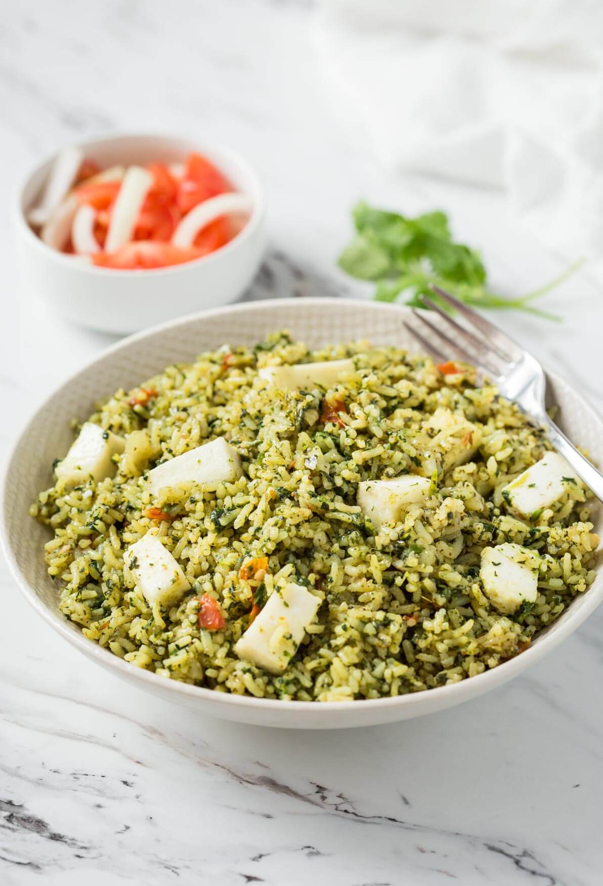 Palak paneer rice in a bowl with metal fork. 