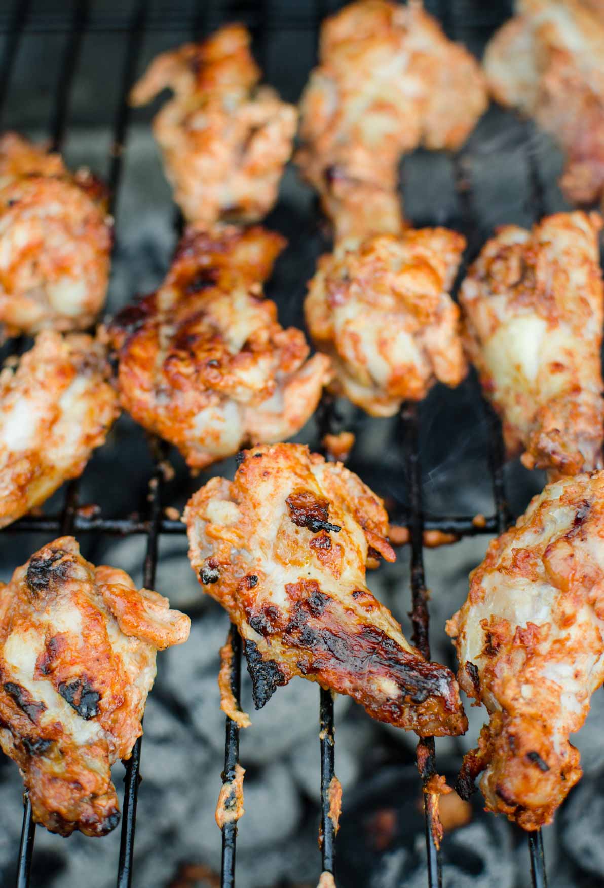 Grilling chicken wings on the barbecue metal rack.