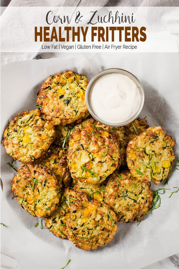 Air fryer zucchini fritters with tahini sauce in a serving bowl lined with parchment paper. Image has text overlay 'Corn & Zucchini Healthy Fritters'. 