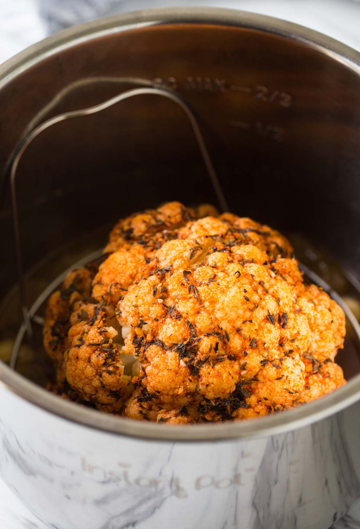 Cook whole cauliflower head in the Instant Pot and serve with delicious creamy gravy. Perfect vegetarian and vegan recipe for the holiday dinner or weeknight healthy meal. | #watchwhatueat #veganthanksgiving #vegan #cauliflower
