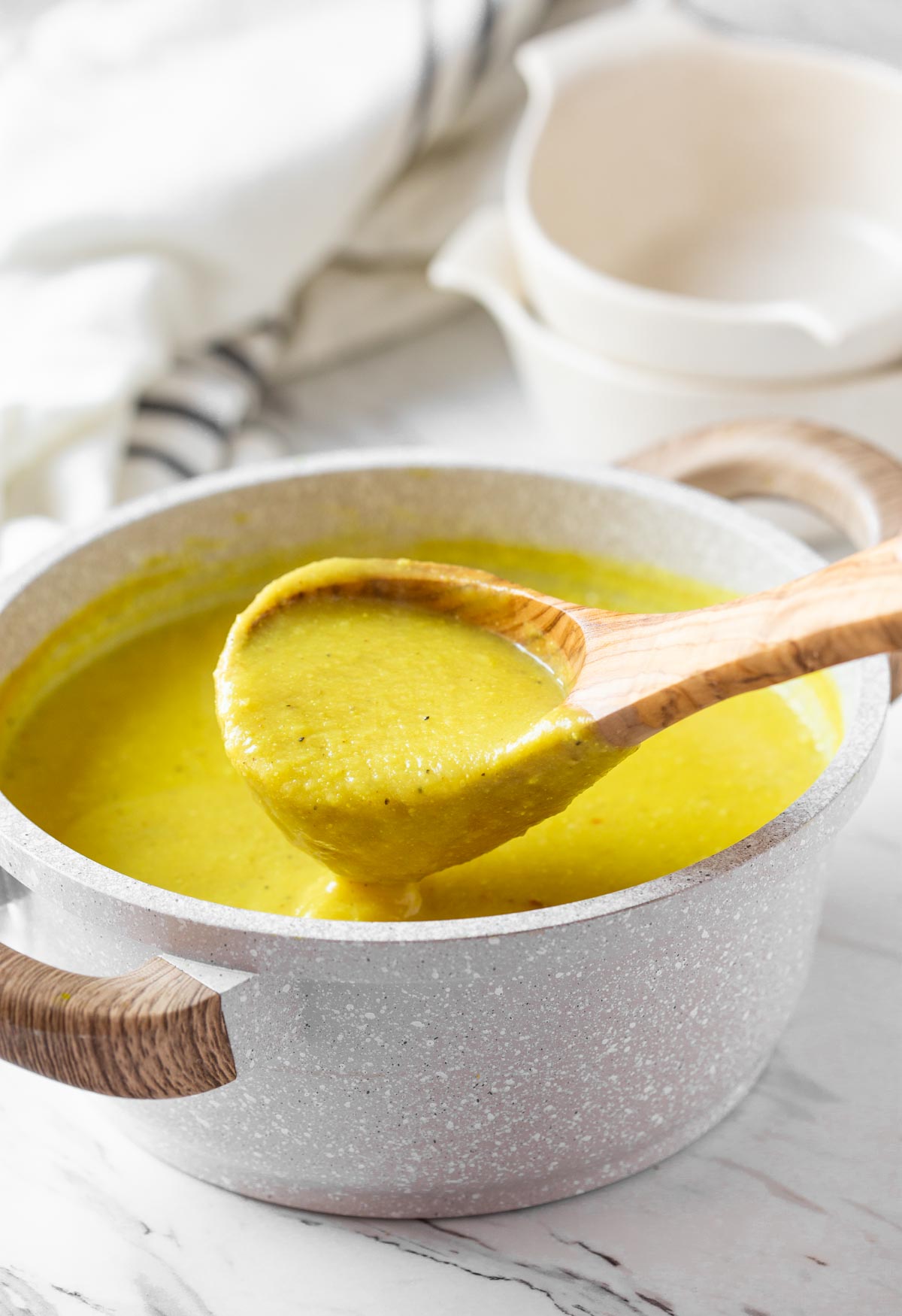 Roasted turmeric cauliflower soup in a pot with wooden ladle.