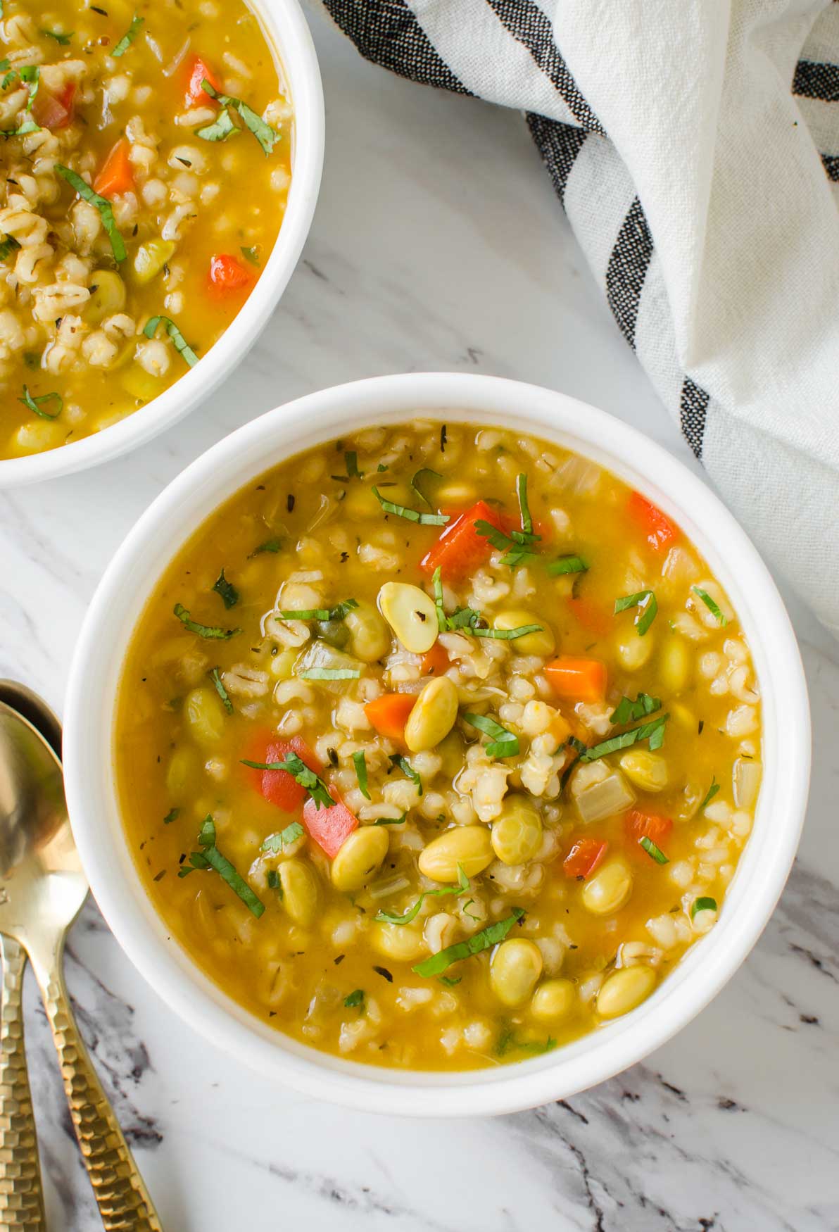 Barley soup with vegetables in a white ceramic soup bowl. 