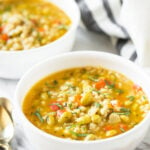 Vegetable barley soup in a ceramic bowl. It's a Pinterest pin with text overlay that reads 'Healthy Instant Pot Vegetable Barley Soup'.