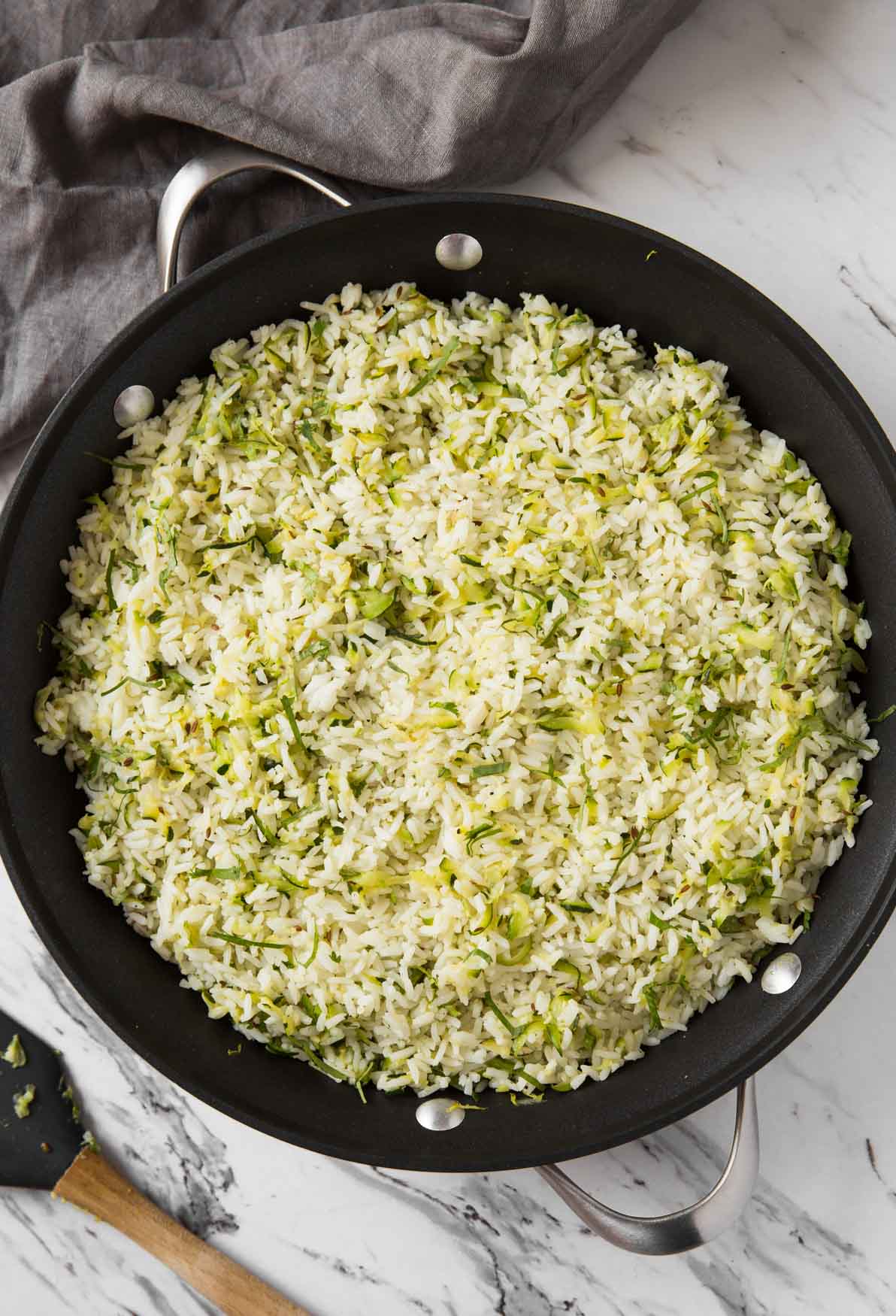 Rice with shredded zucchini in a large frying pan.