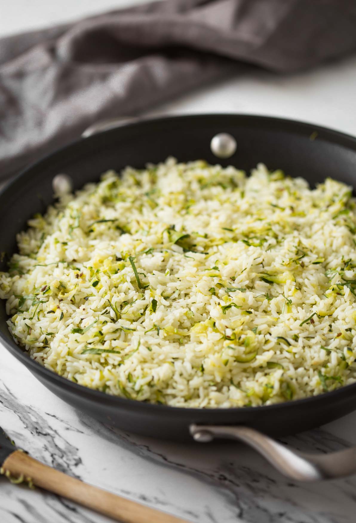 Rice with shredded zucchini in a large frying pan.