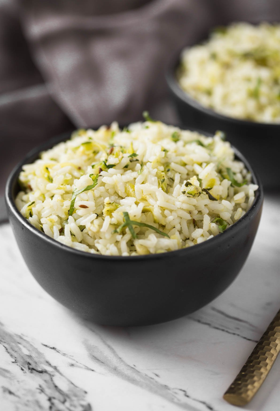 Zucchini rice in a small black ceramic bowl.