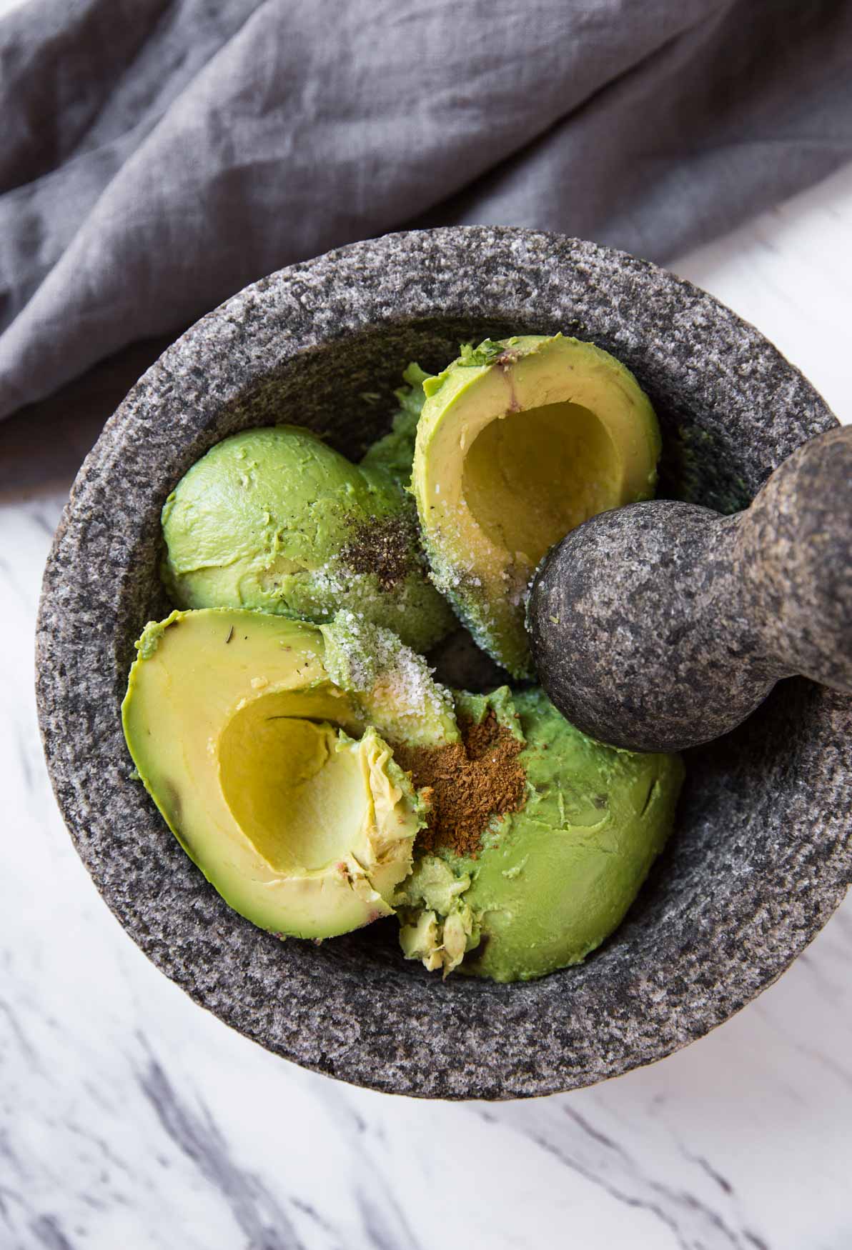 Peeled and pitted avocados in the molcajete for making fresh and healthy guacamole