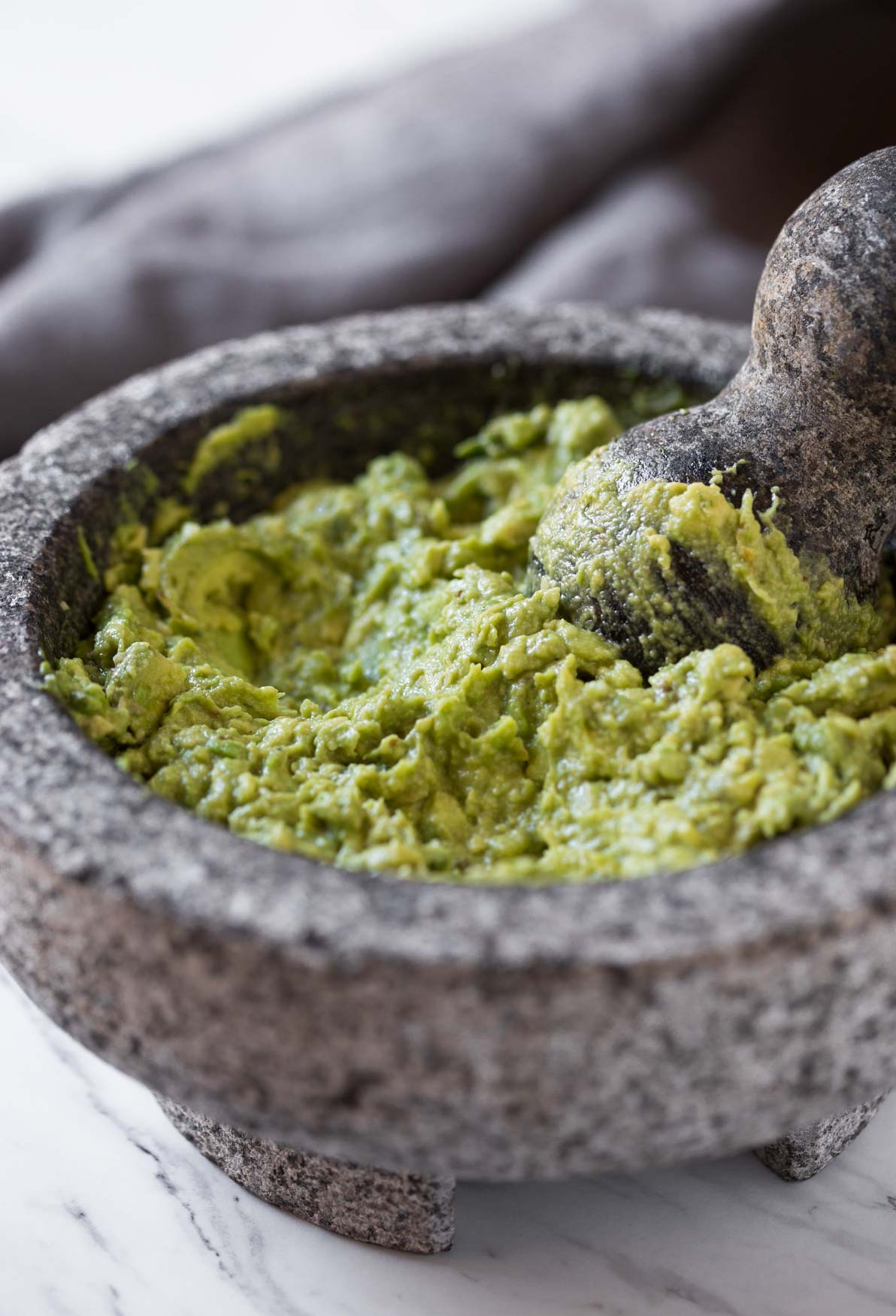 Mashed chunky avocados in the molcajete for making fresh and healthy guacamole