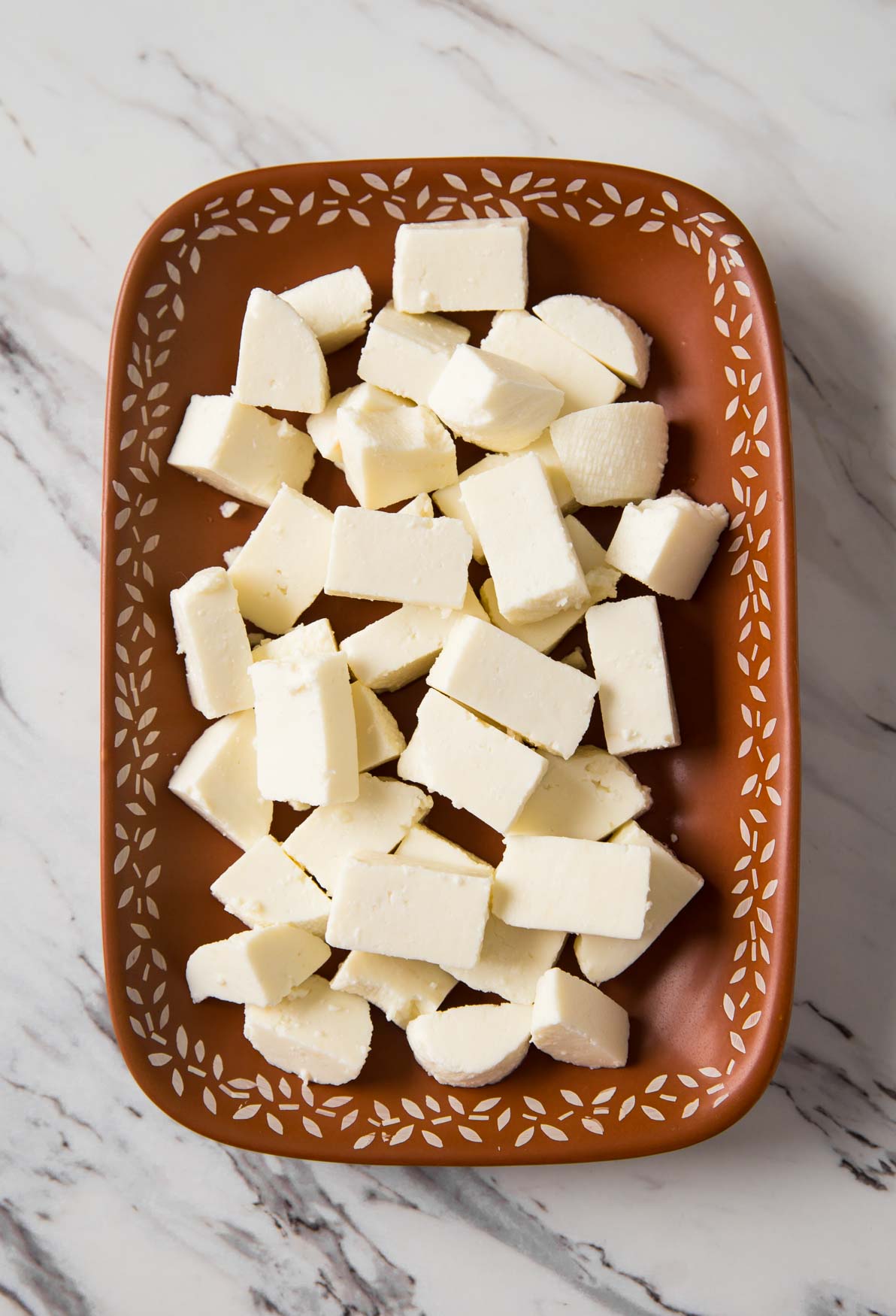 Fresh paneer cubes in a terracotta dish for making palak paneer curry.