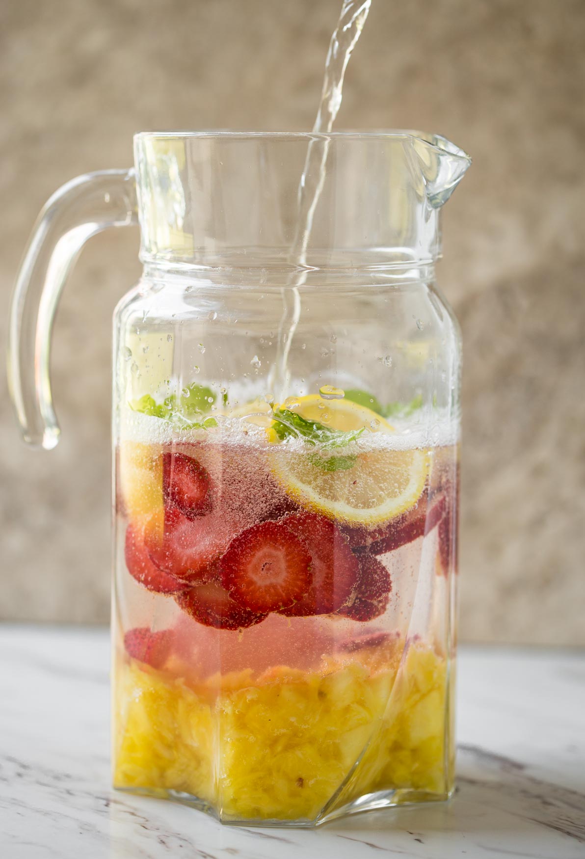 Non alcoholic pineapple strawberry sangria in a large pitcher.