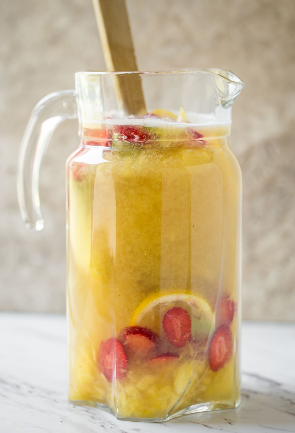 Non alcoholic pineapple strawberry sangria in a large pitcher.