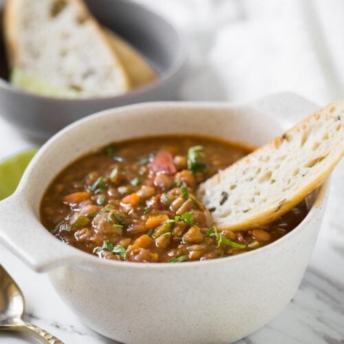 Whole lentil soup in bowl with bread