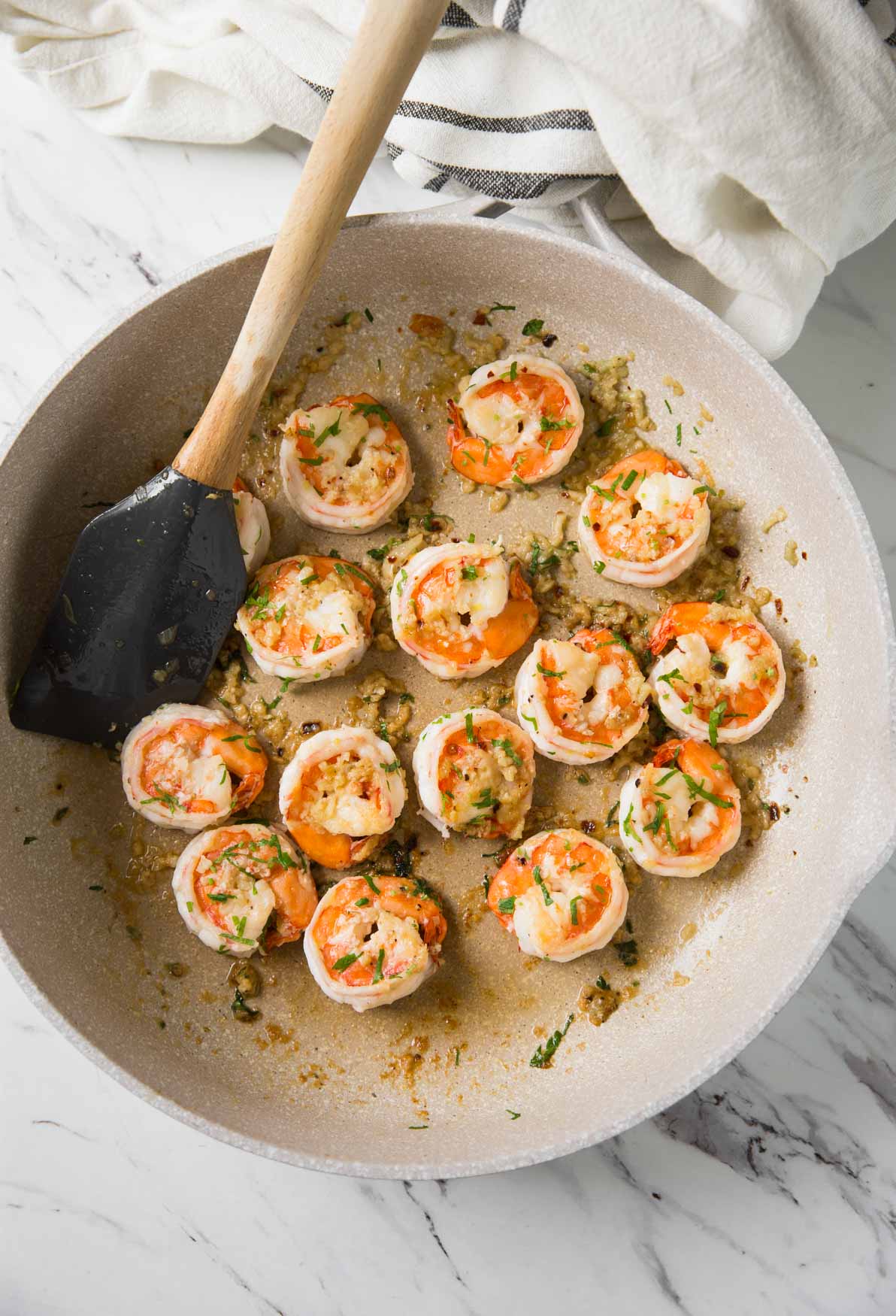 Shrimp stir-fried in a skillet with chili, garlic, and olive oil.