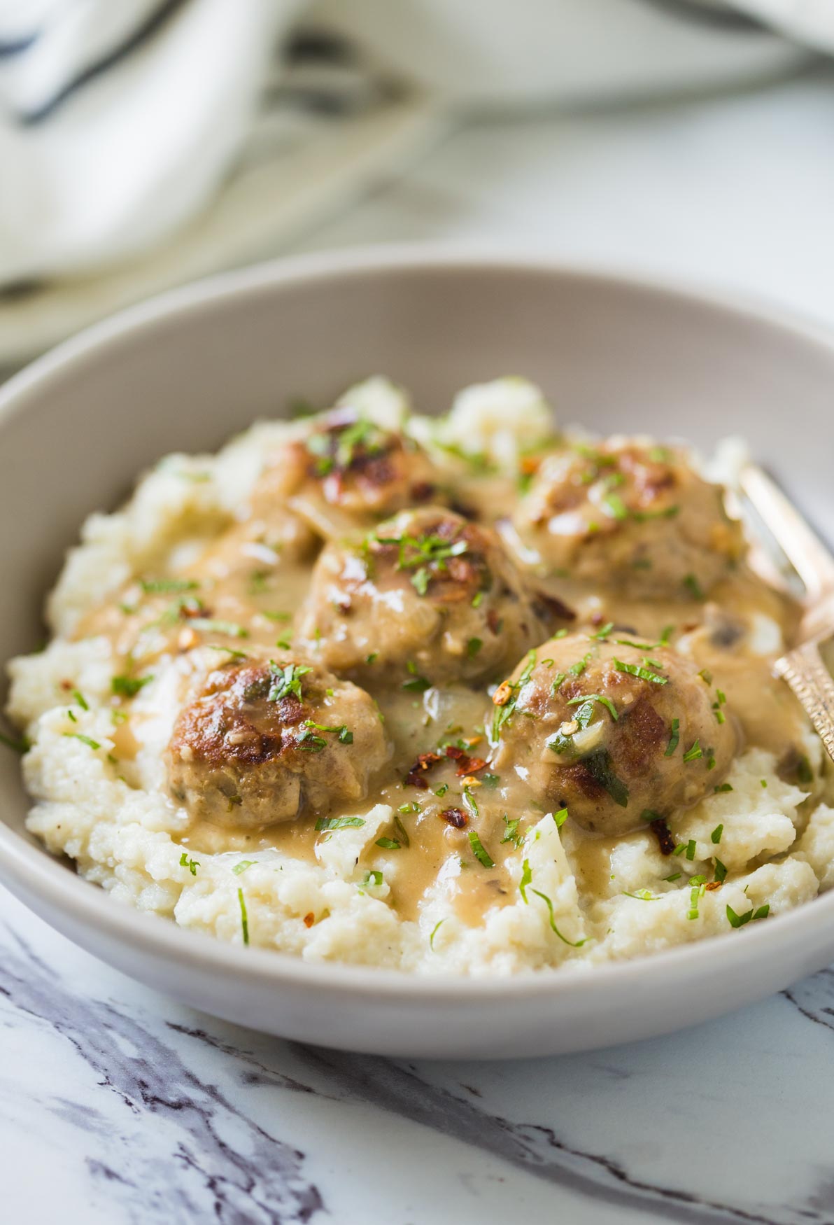 Healthy ground turkey meatballs with gravy and mashed cauliflower in a serving deep dish