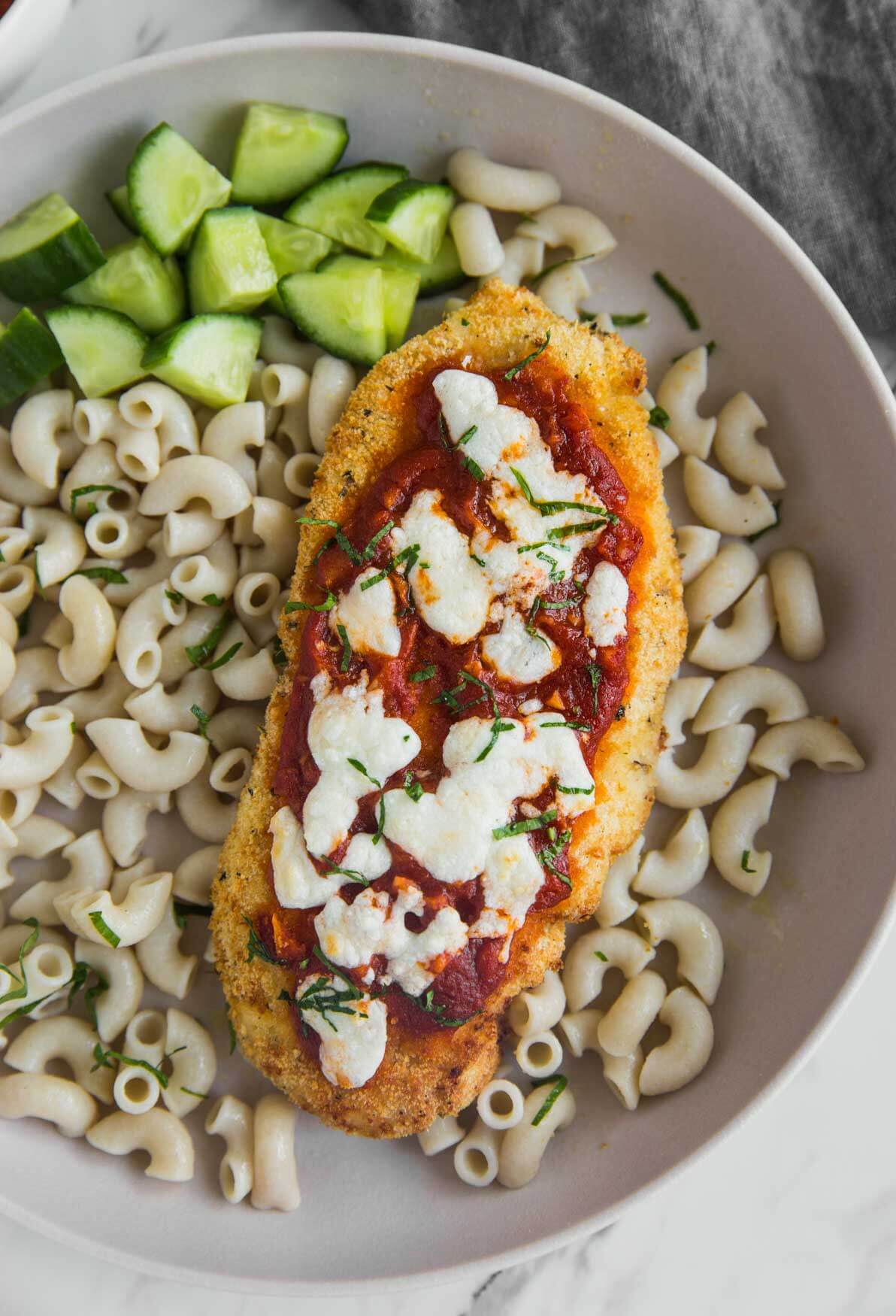 air fryer chicken parmesan in a serving plate with some plain macaroni pasta